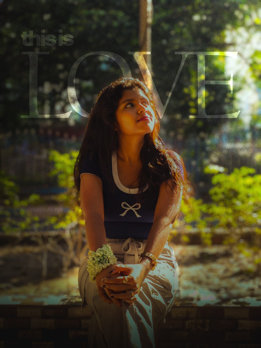 A young woman seated outdoors in green light, with the words this is love across the frame