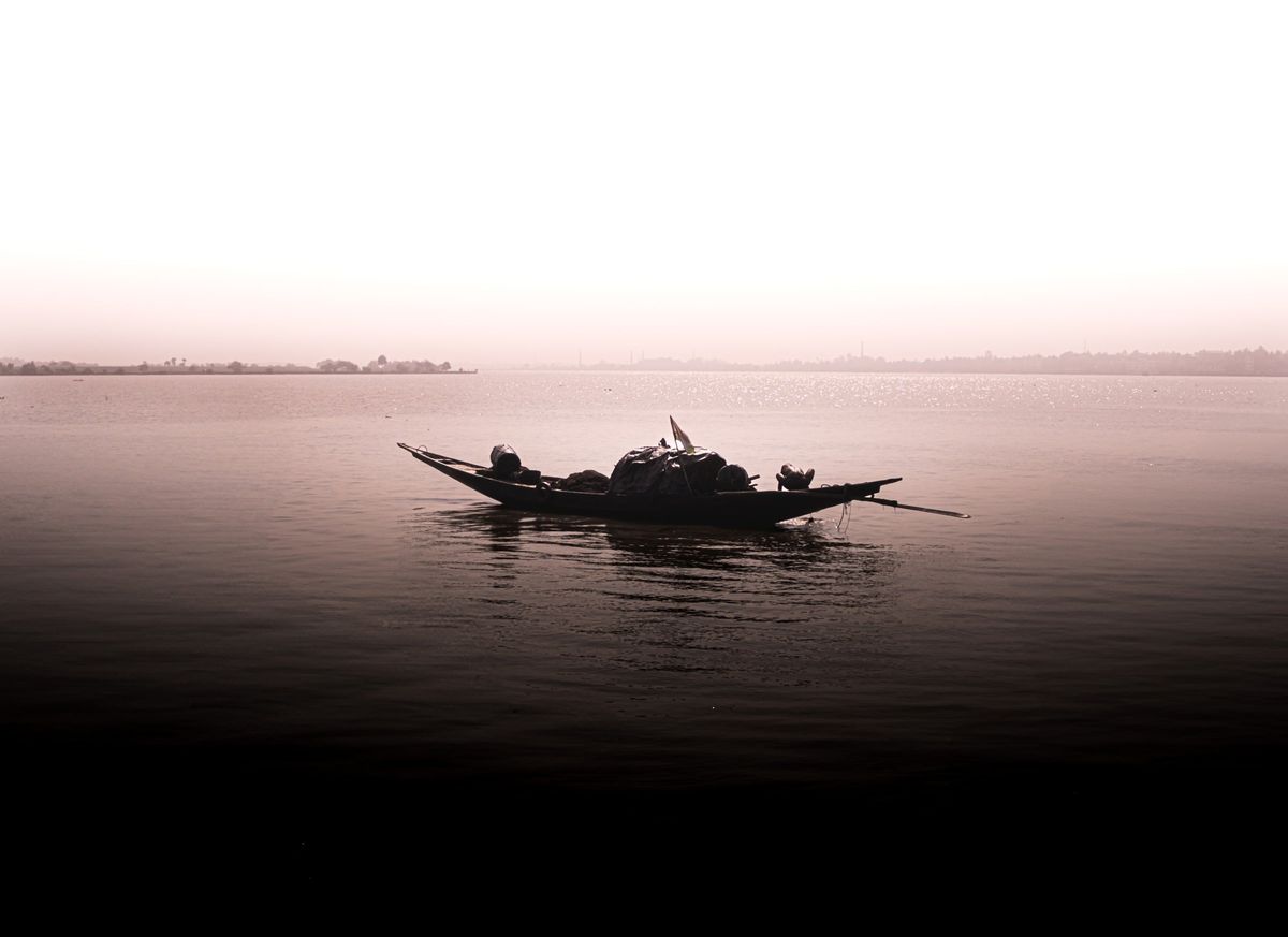 A single loaded boat on flat water under a pale sky