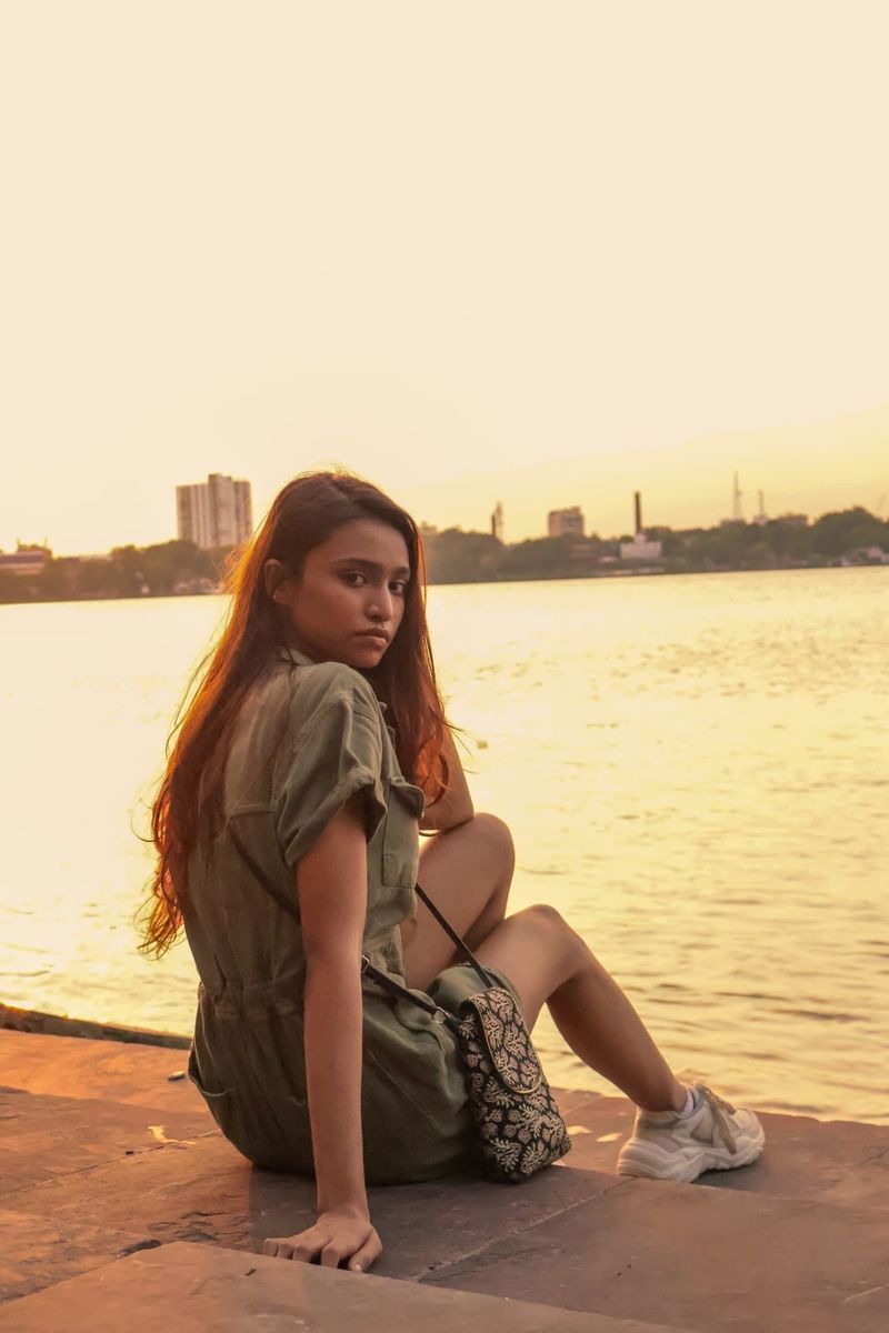 A portrait seated on the riverbank in pale afternoon light