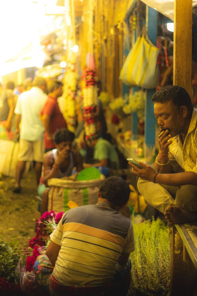 Sellers and buyers among stacked garlands at the flower market