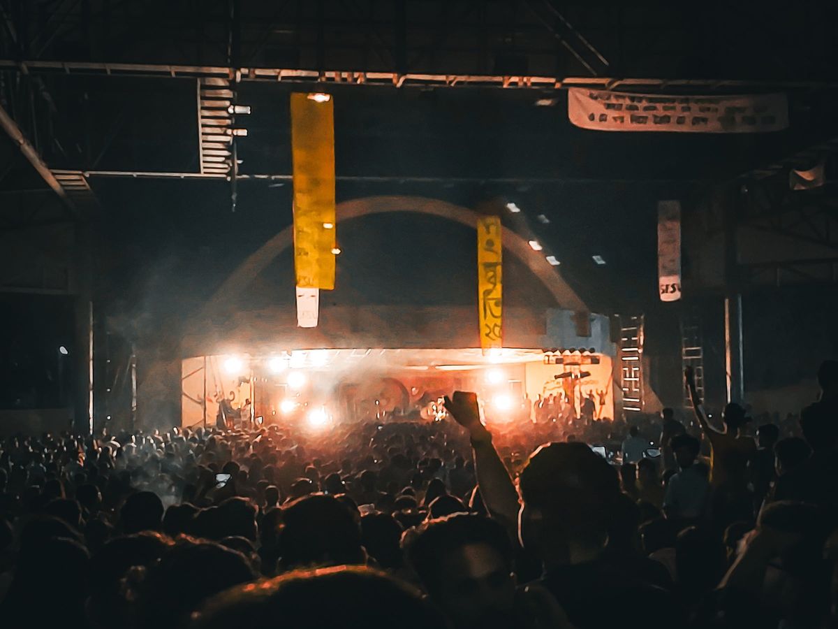 A crowd silhouetted against stage lights at a concert