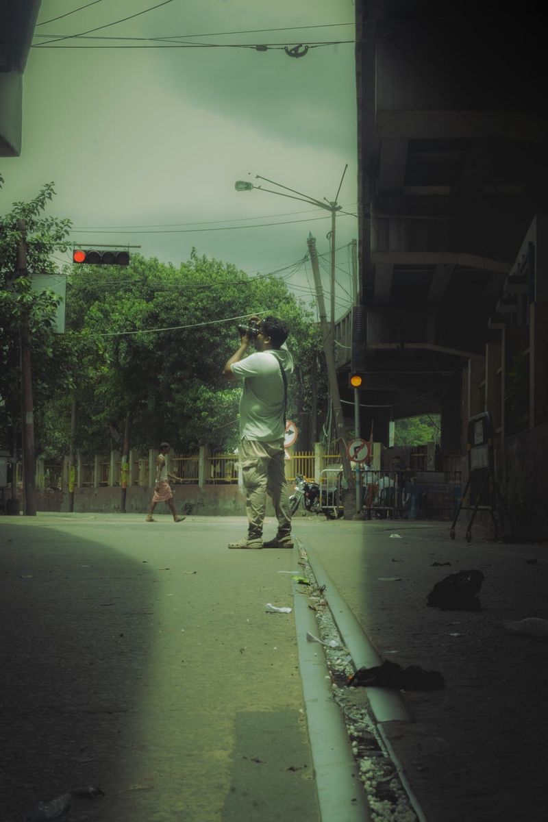 A wet street with tram tracks running away under a green cast