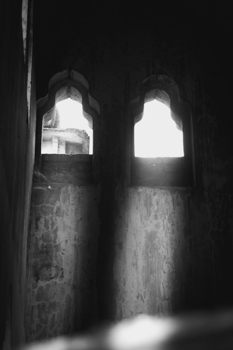Two bright windows in a dark wall, in black and white